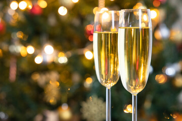 Two champagne flutes on Christmas background with Christmas tree.