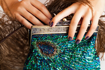woman hands with shiny manicure holding little purse peacok feather, cosmetic and fashion people...