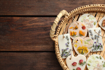 Wicker basket with scented sachets on wooden table, top view. Space for text