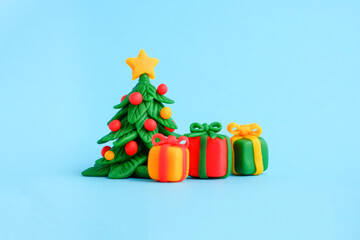 Plasticine figures of Christmas tree and three gift boxes on a blue background. Happy New Year card