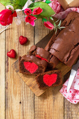 St. Valentine's Day, Birthday or Mother's Day dessert, homemade festive food. Homemade sweet chocolate brownie cake with red heart on a wooden rustic tabletop. Top view flat lay. Copy space.