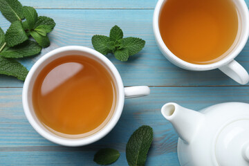 Hot aromatic mint tea on light blue wooden table, flat lay