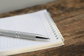 There is a ballpoint pen on a notebook lying on an old blackboard. Concept business