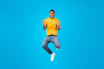 Fototapeta na wymiar Emotional Black Guy Shouting Gesturing Yes In Mid-Air, Blue Background