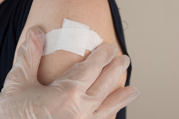 Woman using adhesive bandage plaster on her arm after injection vaccine.