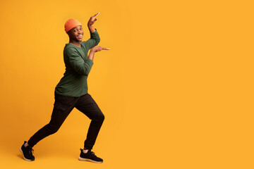 Fototapeta na wymiar Cheerful Funny African American Guy Having Fun And Fooling Over Yellow Background