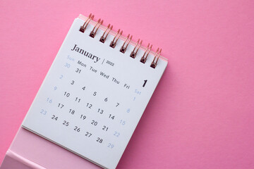 Desktop calendar for January 2022 on a pink background.