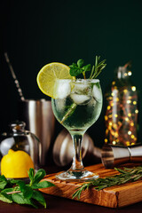 Fresh Mojito cocktail with lemon, rosemary, mint and ice in jar glass on dark blue background. Summer cocktail