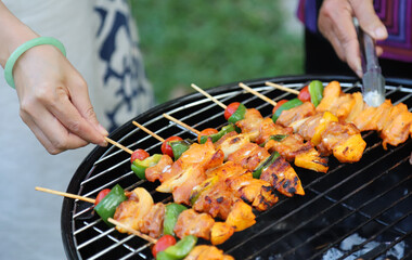 Closeup of  chicken barbecue on gridiron with woman's hands.