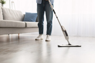 Low section of woman cleaning floor with spray mop