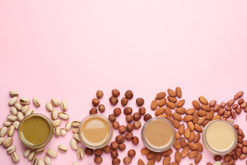 Different types of delicious nut butters and ingredients on pink background, flat lay. Space for...