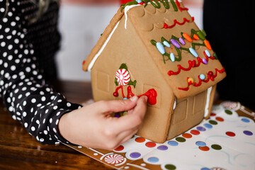 decorating a ginger bread house with candy 