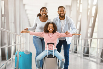 Fototapeta premium Happy black parents traveling with daughter, standing in airport