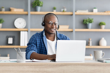 Hotline support service. African american male call center operator in headset working with laptop...