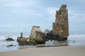 Pecador en la playa sobre antigua torre en Matalascañas