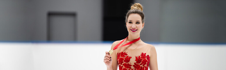 happy figure skater in red dress holding golden medal, banner © LIGHTFIELD STUDIOS