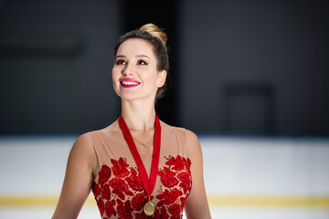 happy figure skater in red dress and ribbon with golden medal