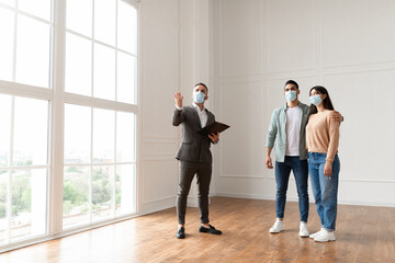 Estate Agent In Medical Mask Showing Buyers New Apartment