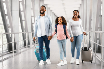 Black family traveling together, holding hands in airport