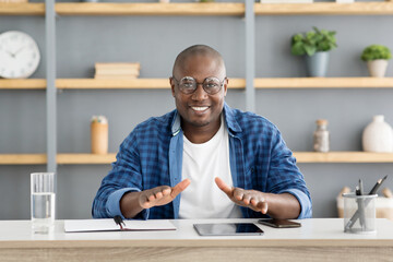 Positive african american man talking and gesturing at camera, having online conference or making video call