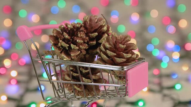 Screensaver pine cones in a cart against a background of Christmas lights. Copy space. Multicolored lights out of focus. Beautiful footage, video for intro, transition, intro. UHD 4K.
