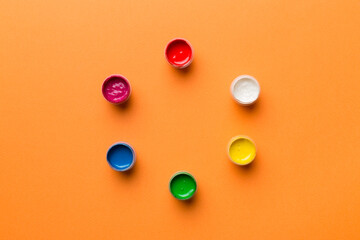 jars with gouache of different colors on Colored background. hobby painting. Top view with empty space. workplace for creativity. home teaching concept drawing