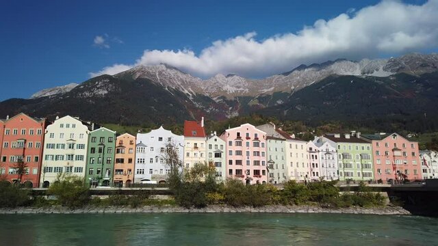 Colorful houses of Innsbrucks old town with 'Inn' river infront and peaks of the Nordkette in Austria