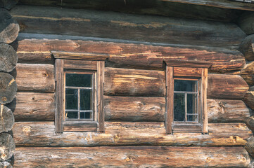 Wooden rural house made of huge logs. This house was built in the second half of the XIX century. The diameter of the logs reaches 80 centimeters (32 inches). Cracked dark logs of a wooden house.