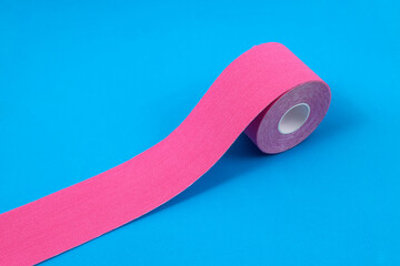 Pink kinesiology tape on the blue surface.Tape for sports recovery, face taping - obrazy, fototapety, plakaty