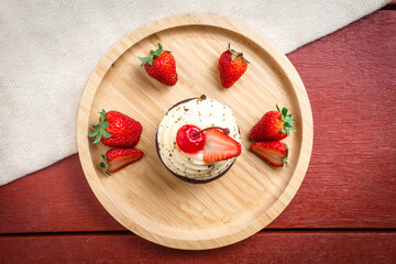 Muffin with strawberries and cherry on a bamboo plate. Top view.