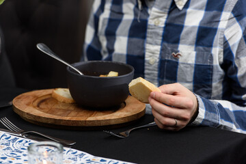 Man eating seafood spicy soup with potatoes, shrimps, herbs and fish from a picad closeup in a pan served with toast. horizontal. Served in a restaurant