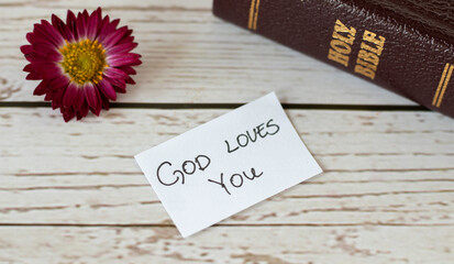 God Jesus Christ loves you handwritten message inspiring quote with closed Holy Bible Book, and...