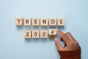 Hand of woman flips wooden blocks and change the 'TRENDS 2021' to 'TRENDS 2022'.