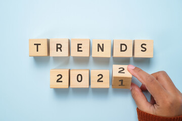 Hand of woman flips wooden blocks and change the 'TRENDS 2021' to 'TRENDS 2022'.