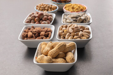 Peanuts in shell in selective focus. Background of dried mulberry, hazelnut, pistachio, grape, almond, yellow chickpea and sunflower seeds.