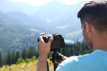 Man taking photo of nature with modern camera on stand outdoors