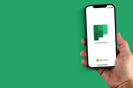 Male hand holding a smartphone with Microsoft Planner app on the screen. Green background. Rio de Janeiro, RJ, Brazil. December 2021