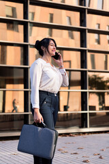 woman talking by phone in front of an office building