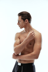 Fototapeta premium Half-length portrait of young handsome shirtless sportive man wearing black boxer-briefs standing isolated on white background.