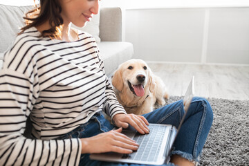 Young woman at home with laptop and labrador