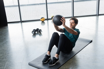 Fototapeta premium Sportsman working out with slam ball on fitness mat in sports center