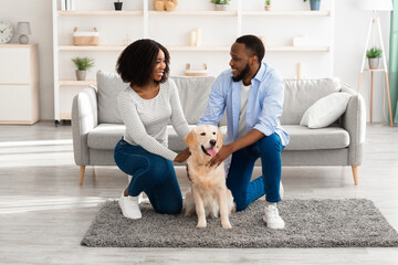 Black spouses spending time at home patting labrador