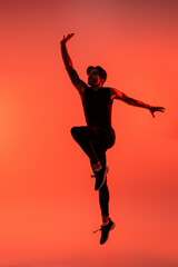 Fototapeta na wymiar Athletic sportsman in black sportswear jumping on red background