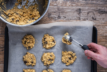 Scooping oatmeal cookie dough onto a sheet pan - 476624375