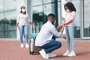 Black family traveling with kid, man using sanitizer on girl