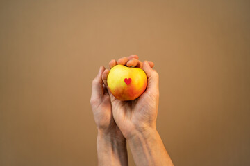 Men hand holding and showing a apple on brown background