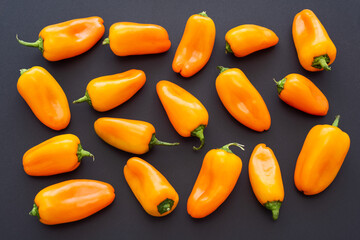 Top view of orange mini sweet peppers on black background. Healthy food.