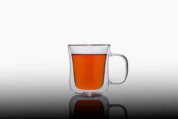 Double glass cup of tea on a black background. Glass cup of tea on the mirror. Double glass cup isolated. Modern glass tea cup.