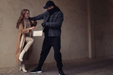 Woman fighting with thief while he trying to steal her bag outdoors, space for text. Self defense concept
