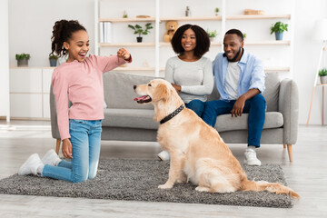 Happy black girl giving a treat to her labrador